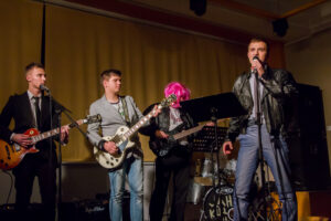 Suur teatriõhtu. Gümnaasiumi teatriõhtut juhtis gümnasistide rokkbänd, kus basskitarristina mängis roosas parukas kaasa õppealajuhataja Maidu Varik.