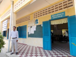 Mey Sovoeun oma algkooli õpetajate toa lävel. Kambodža riigikoolid on oma välisilmelt äravahetamiseni sarnased.