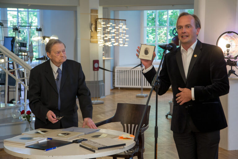 TÜ õppeprorektor Mart Noorma kinkis Tullio Ilometsale plaadi, kuhu multimeediatalitus oli kogunud temast fotosid läbi aastakümnete. Foto: Andres Tennus / TÜ