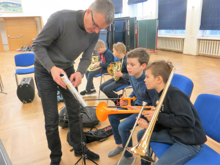 Kolmanda klassi lapsed harjutavad õpetaja Gunnar Pettaigi käe all, põsed punnis, pillimängu, et riigi 100. sünnipäeva aktusel juba ise olla orkestrantide seas. Fotod: Sirje Pärismaa